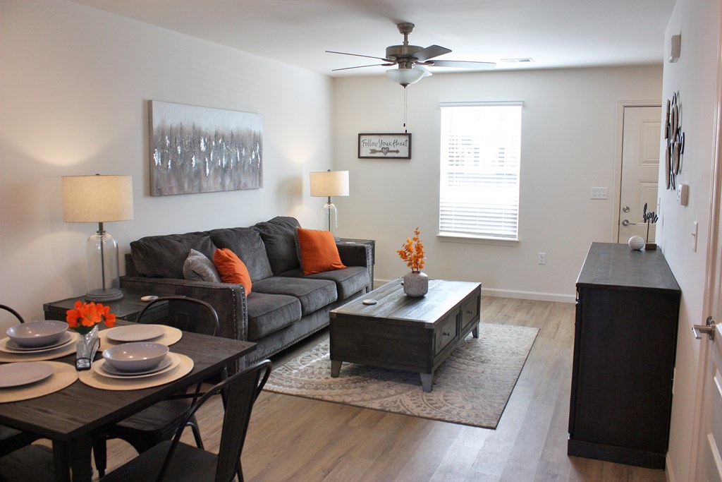 A living room with a black couch, a coffee table, and a dining table with chairs.