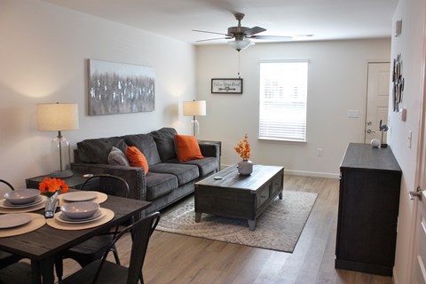 A living room with a black couch, a coffee table, and a dining table with chairs.