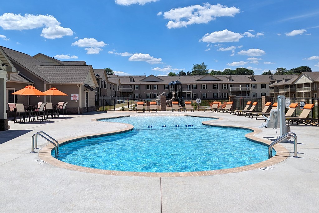 A large outdoor swimming pool surrounded by lounge chairs and umbrellas.