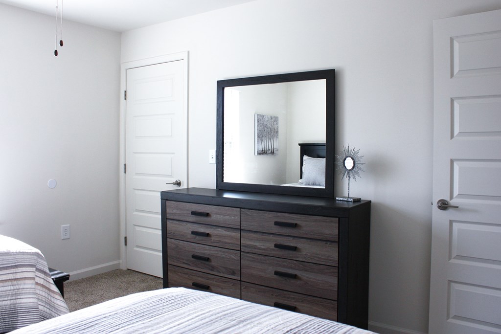 A bedroom with a bed, dresser, and mirror.