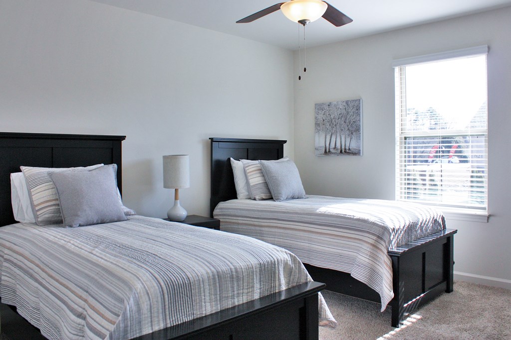 Two beds with pillows and a ceiling fan in a room.