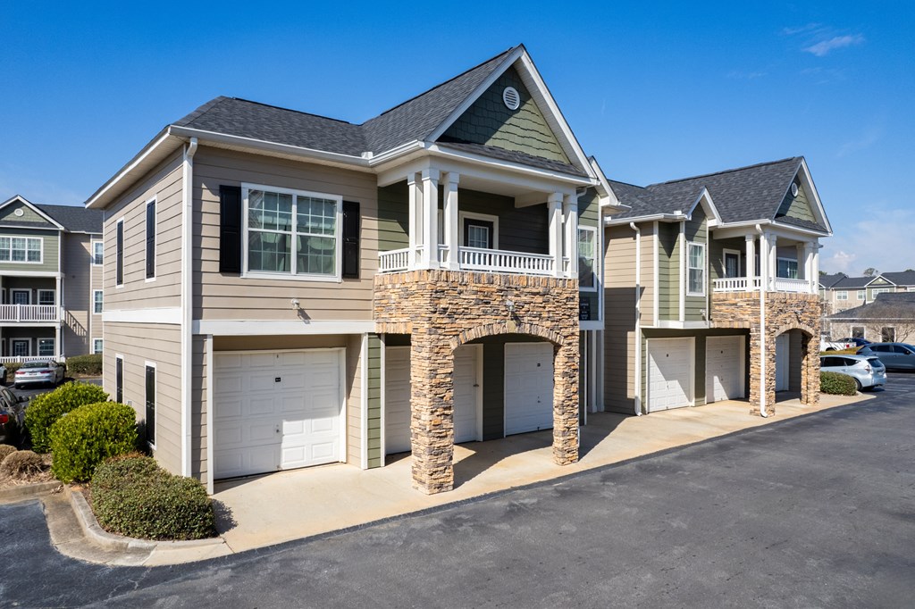a tan and green house with two garages and a balcony