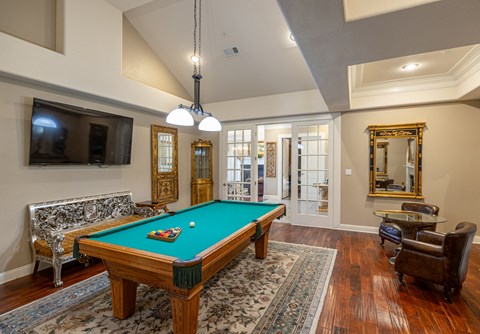 a living room with a pool table and a tv