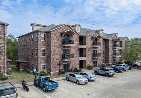 an apartment building with cars parked in a parking lot