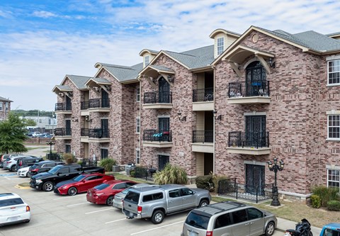 a brick apartment building with cars parked in the parking lot