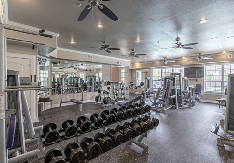 a gym with weights and cardio equipment and ceiling fans