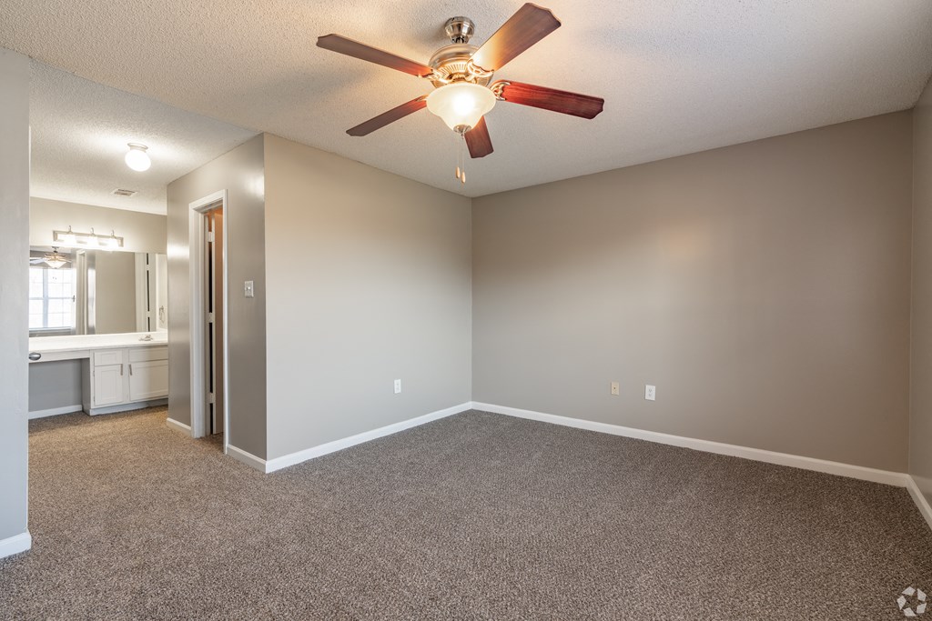 an empty living room with a ceiling fan