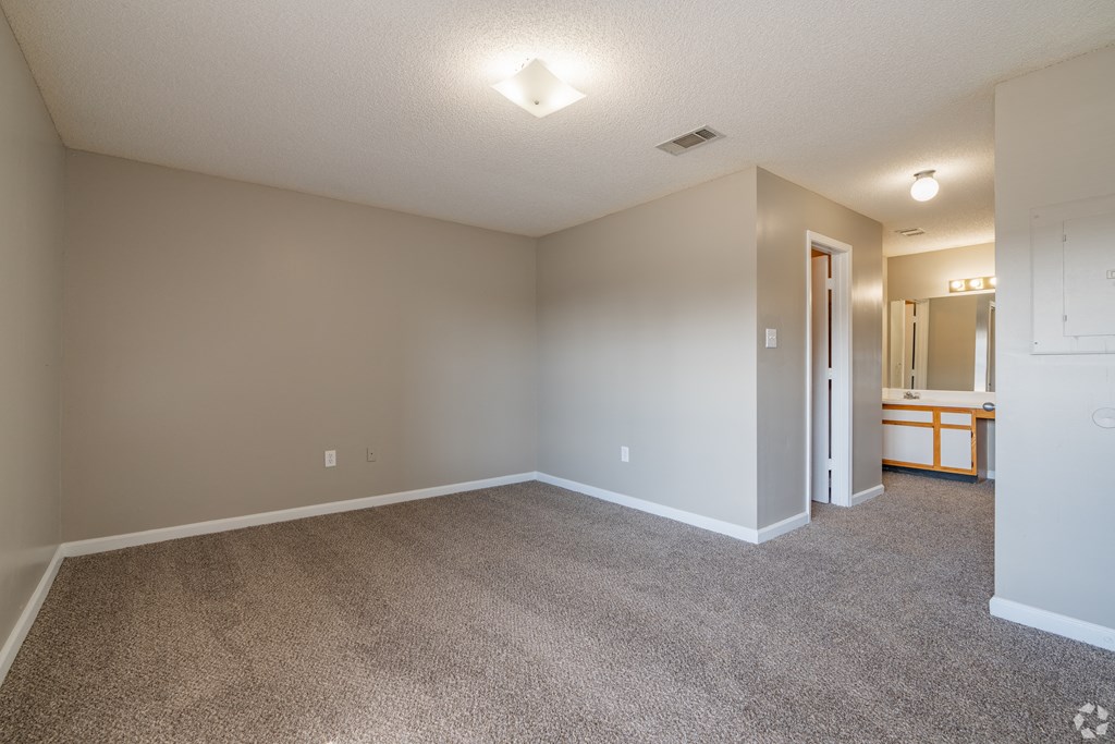 an empty living room with carpet and a door to a bathroom