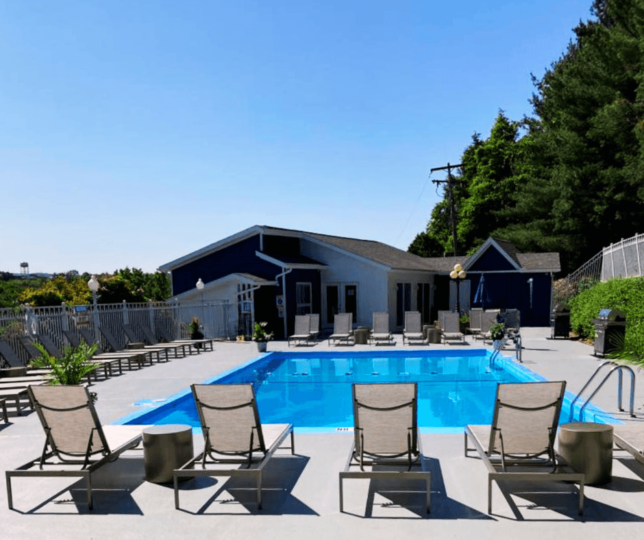 a swimming pool with deck chairs and a building in the background