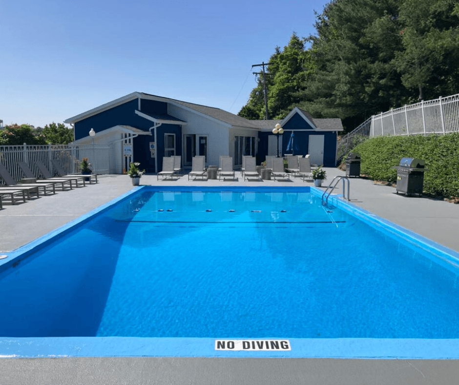 a large swimming pool with lounge chairs and a building in the background