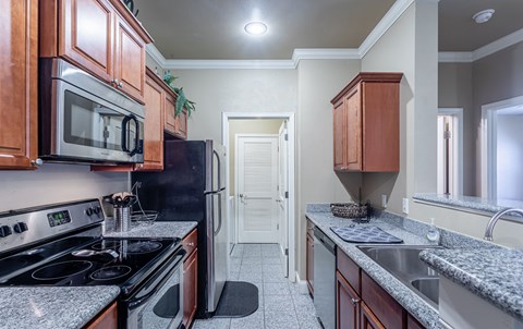 an empty kitchen with granite counter tops and a black stove and refrigerator