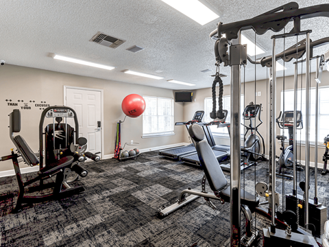 spacious gym with cardio machines and weights at the enclave at woodbridge apartments gym room