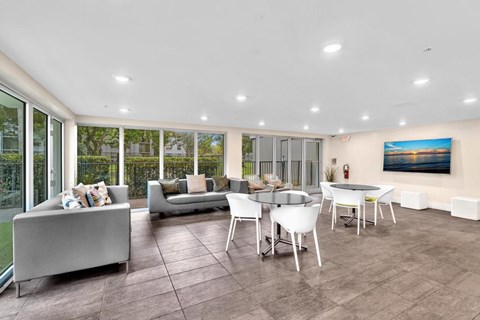 A modern living room with a grey sofa, white chairs, and a painting on the wall.