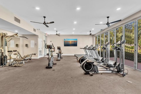 A gym with a variety of exercise equipment including treadmills, stationary bikes, and elliptical machines.