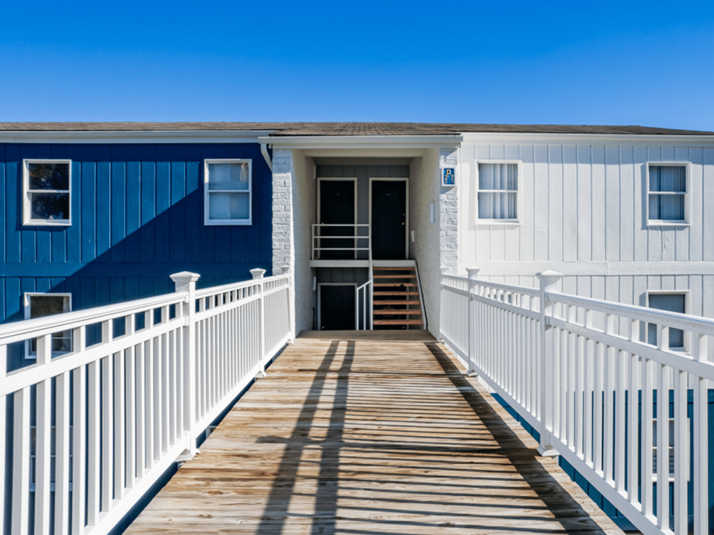 a blue and white house with a porch and a boardwalk