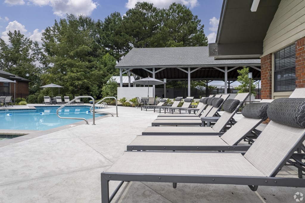 a pool with lounge chairs and umbrellas in front of a building