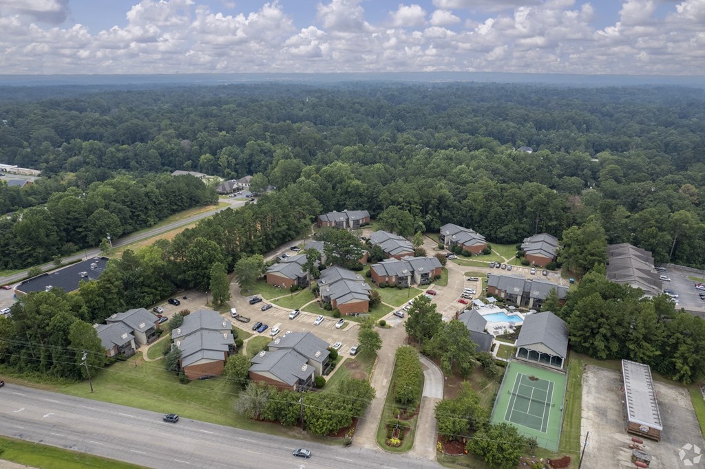 arial view of a neighborhood with green trees and a blue sky