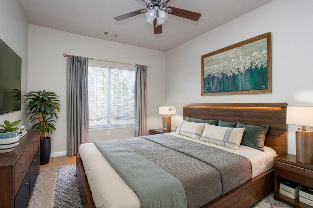 A bedroom with a large bed and a painting on the wall.