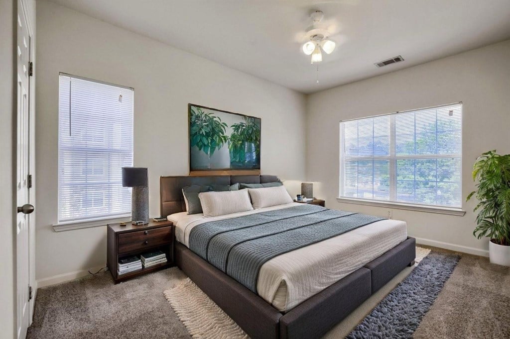 A bedroom with a large bed, a nightstand with a lamp, and a painting on the wall.