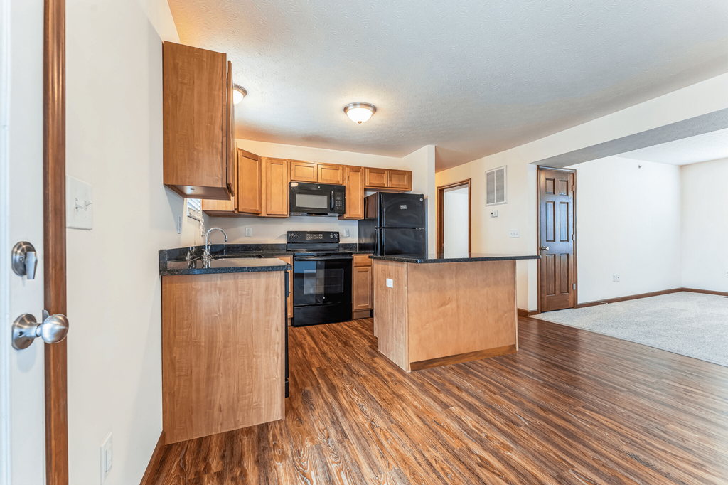 the view of a kitchen and living room with wood flooring