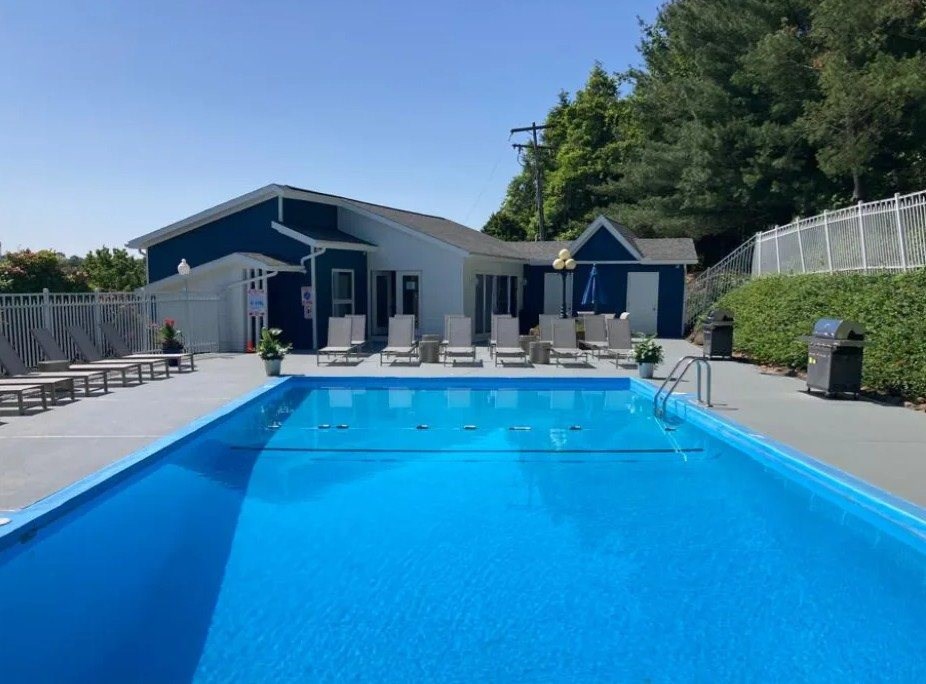 A blue swimming pool in front of a house.