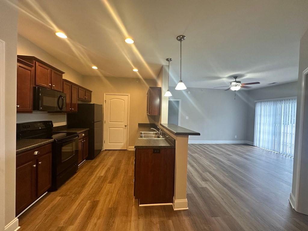 A kitchen with wooden cabinets and a black refrigerator.