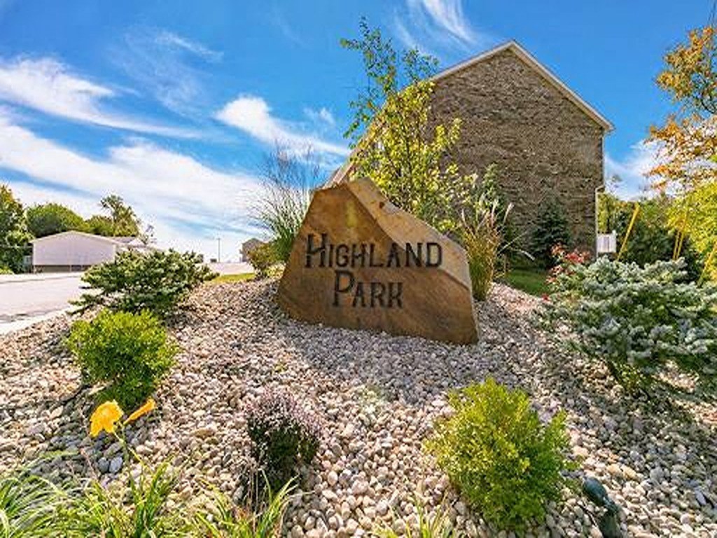 a sign for highland park in a rock garden