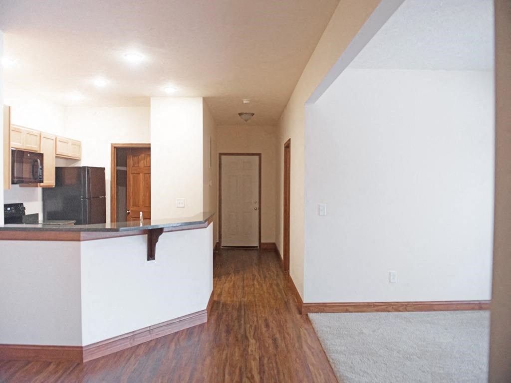 an empty living room and kitchen with a hard wood floor
