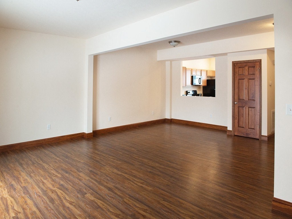an empty living room with wood flooring and a wooden door