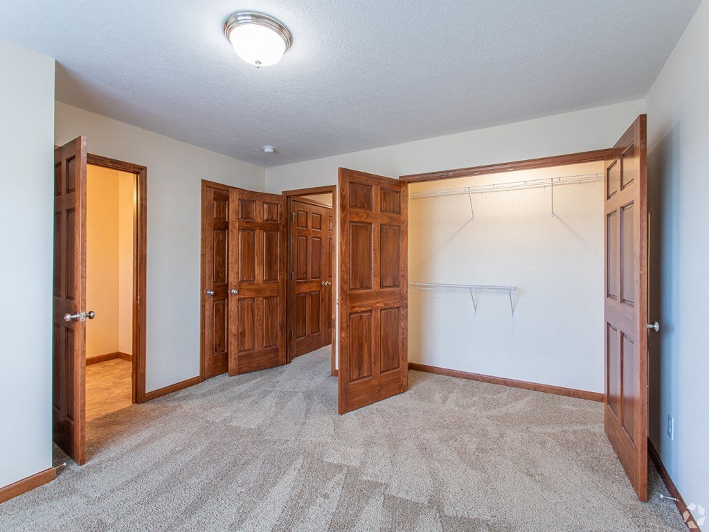 an empty bedroom with wooden doors and a carpeted floor