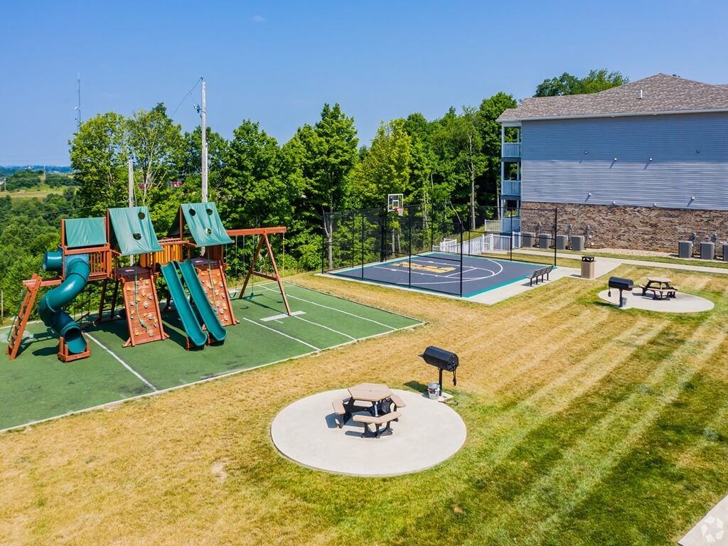 a playground with a tennis court and a basketball court in a backyard