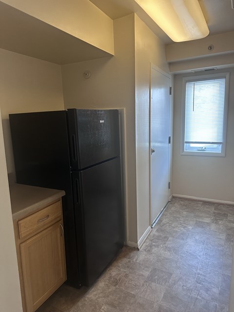 A black fridge in a kitchen with a wooden drawer.