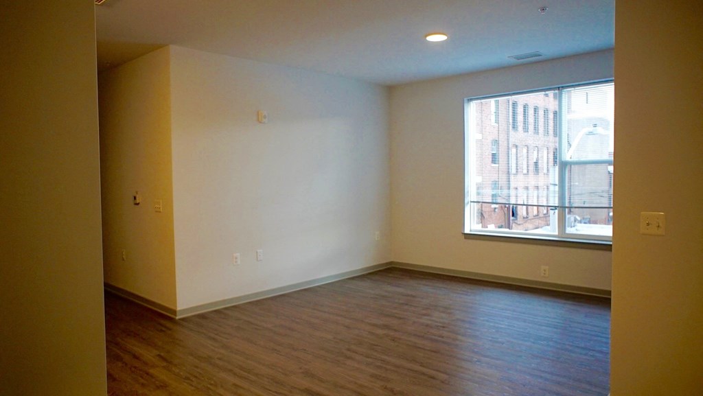 an empty living room with wood floors and a large window