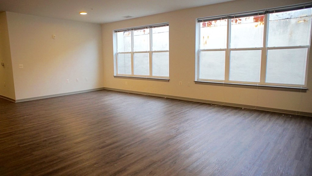 an empty living room with wood floors and large windows