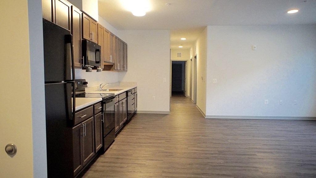 an empty kitchen with wood flooring and black appliances