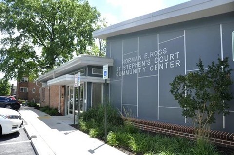 A building with a glass facade and a sign that reads "Norman E. Ross Stephen's Court Community Center.".