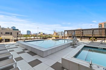 two hot tubs on the rooftop of a building with a city in the background
