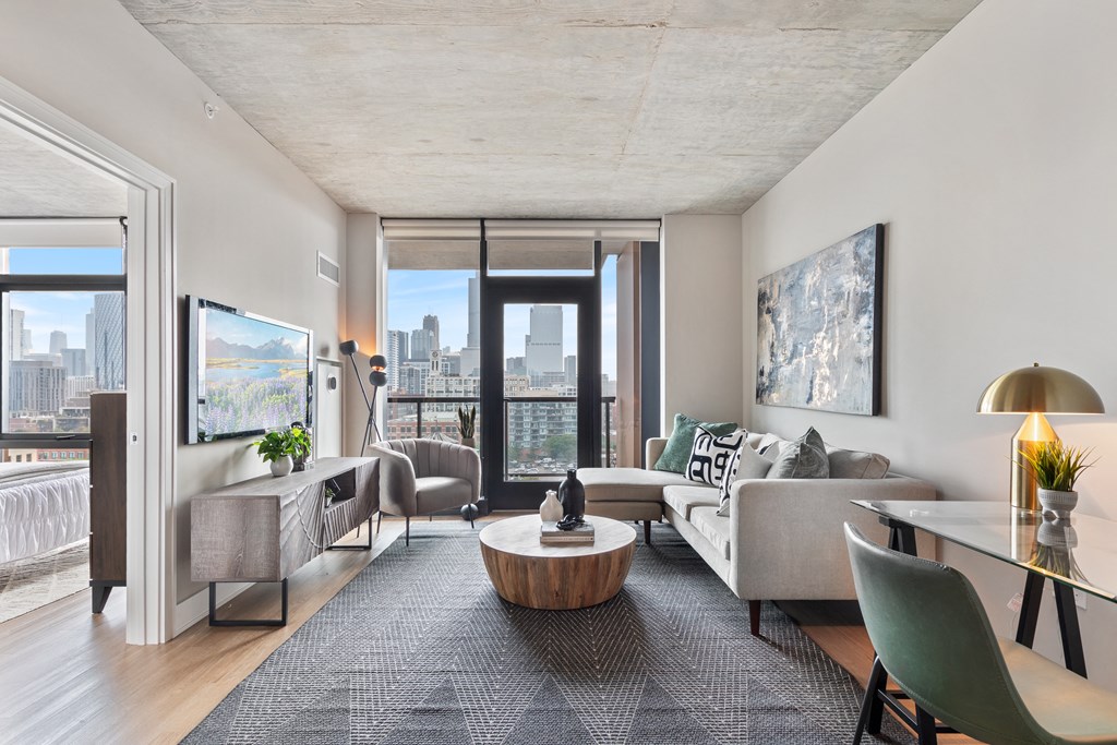 a living room with white walls and a large window with a view of a city