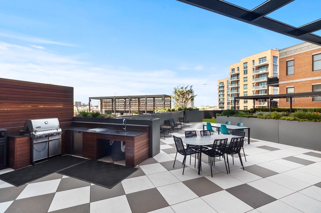 a rooftop patio with a grill and a table and chairs