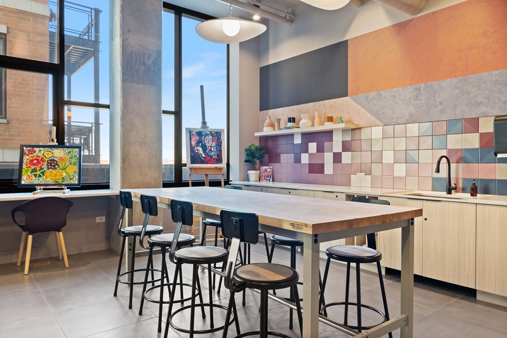 a communal table with chairs in a kitchen with large windows