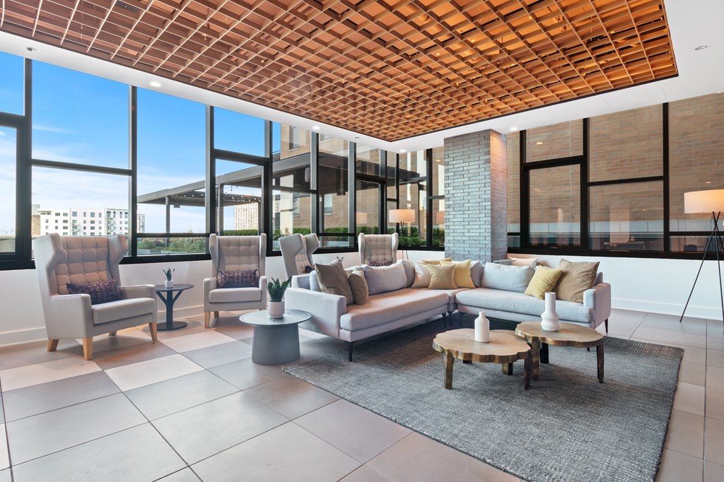 a living room with a couch and chairs in front of large windows