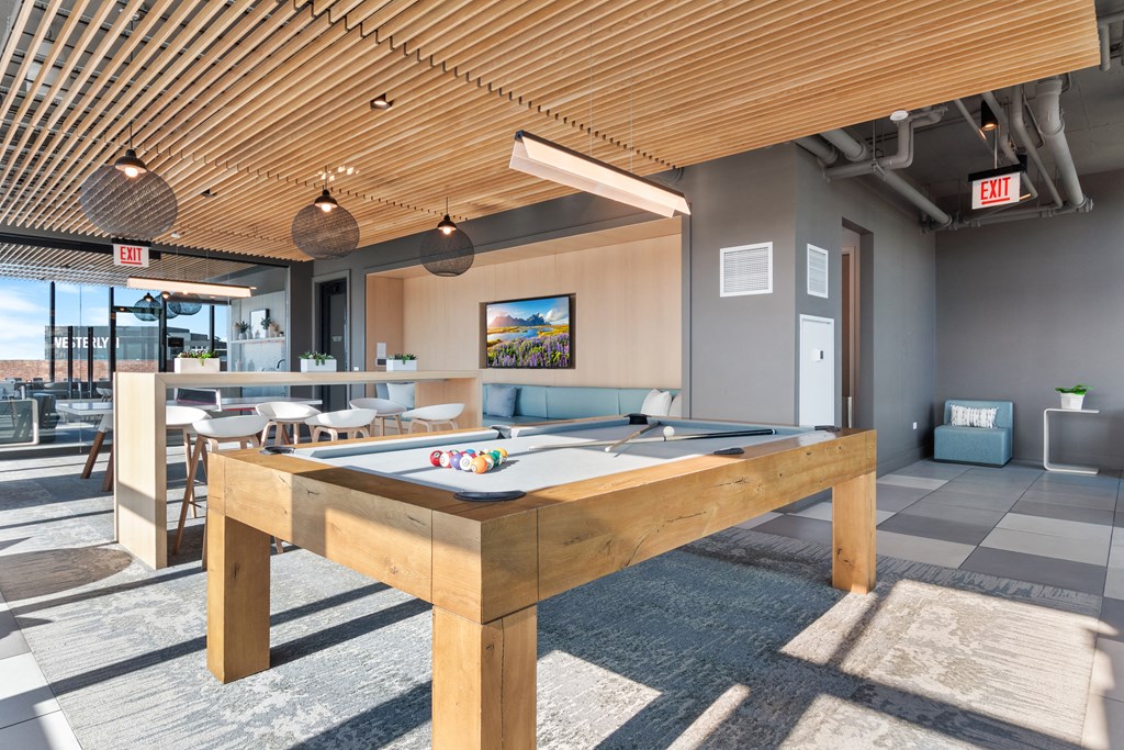 a pool table in a clubhouse with a bar in the background