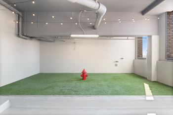 a red fire hydrant in a room with fake grass