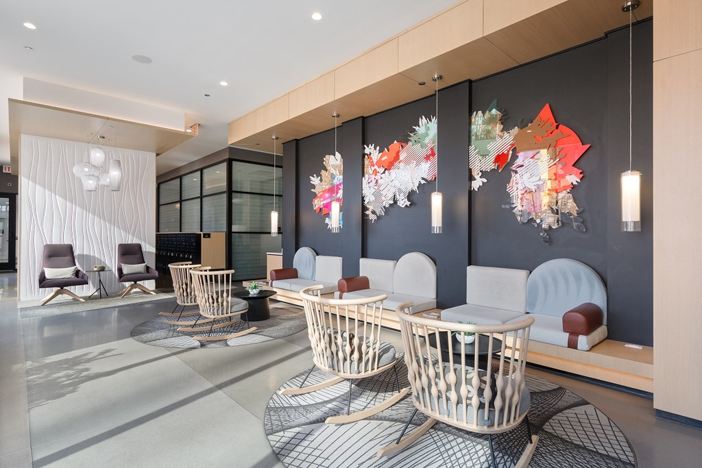 a lounge area with chairs and tables and artwork on the wall