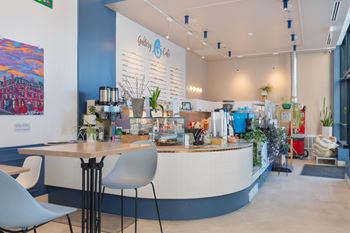 a cafe with a round table and chairs in front of a counter with coffee machines