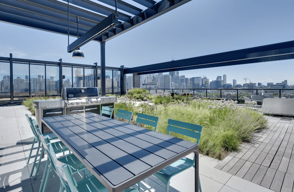 a table and chairs on a roof terrace with a grill and a view of the city