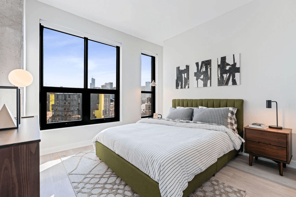 a bedroom with a large window and a bed with a green headboard