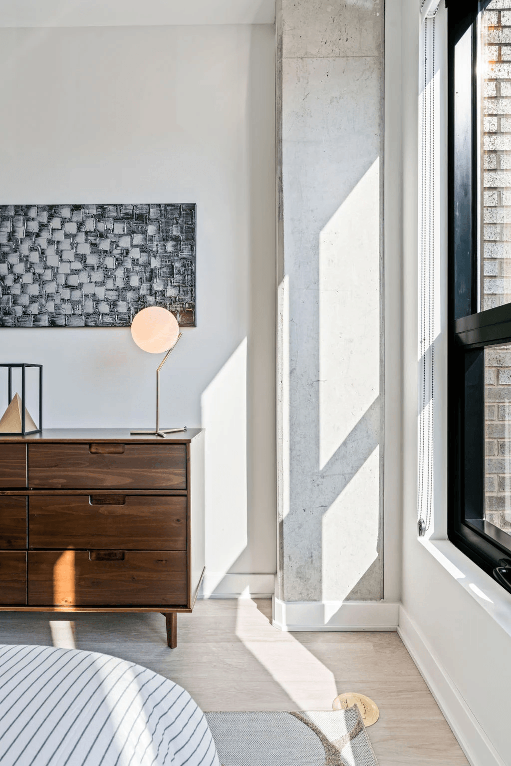 a bedroom with a bed and a dresser with a lamp on top of it