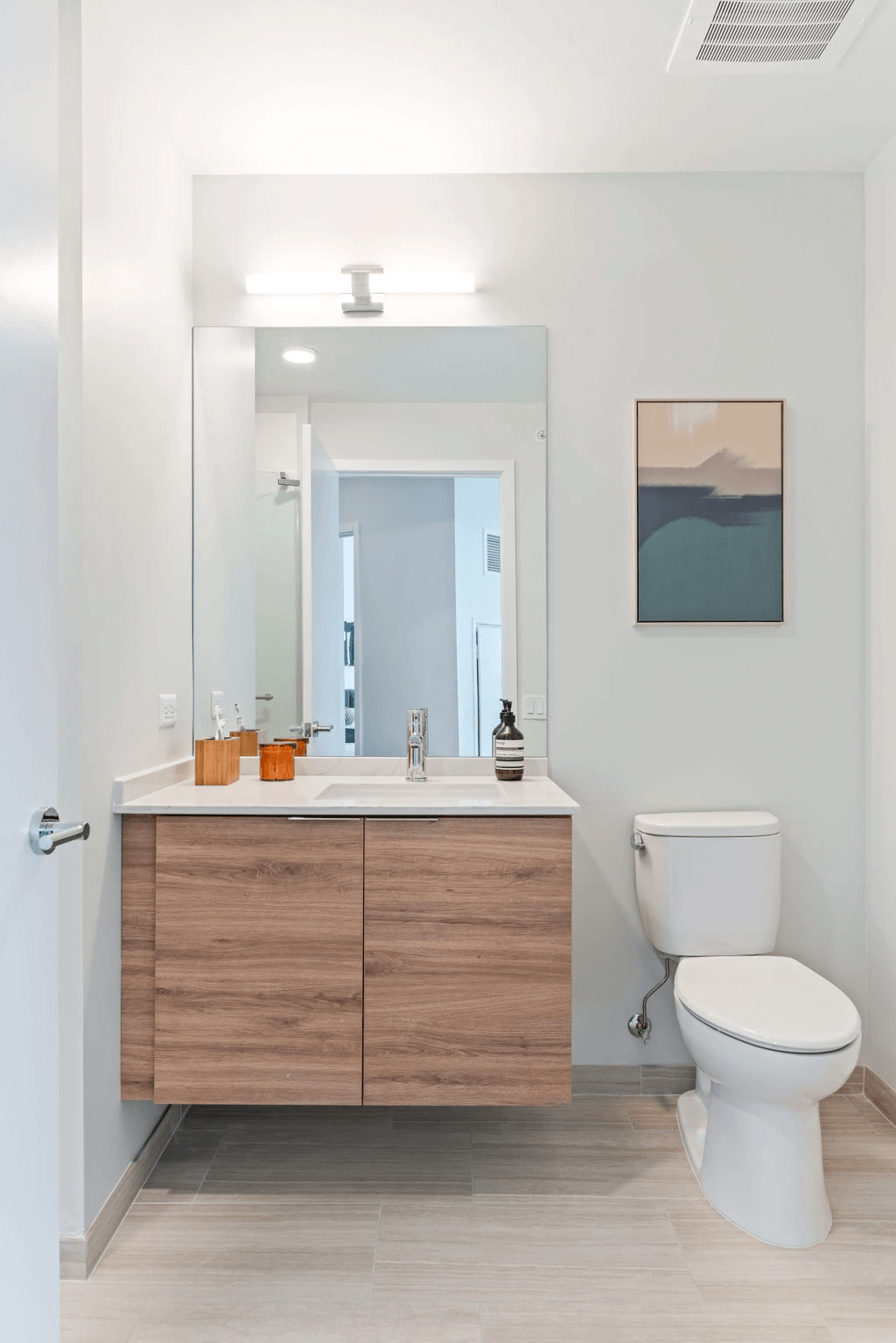 a bathroom with white walls and a wooden vanity with a white toilet