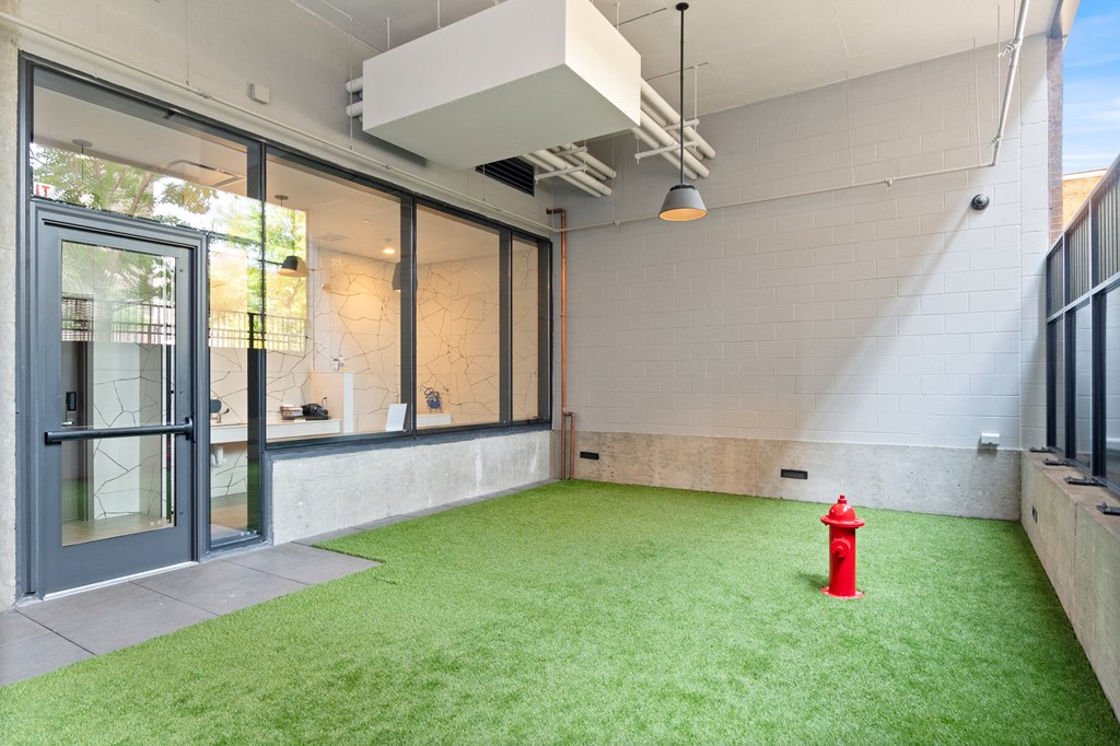a fire hydrant sits in the corner of a room with green grass and a glass door